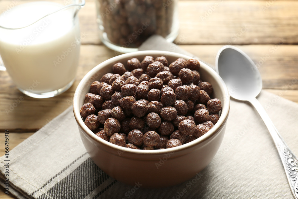 Chocolate corn balls in bowl and jug with milk on wooden table Chocolate corn balls in bowl and jug with milk on wooden table
