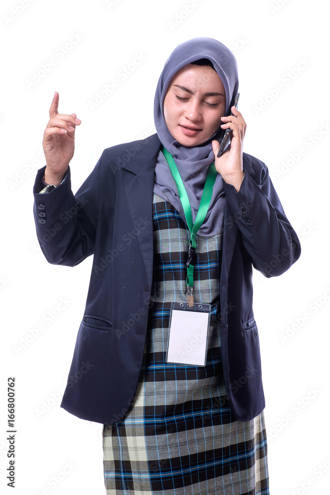 A beautiful, confident Muslim woman with a happy expression wearing hijab, suit and wearing a blank ID tag or name card on a lanyard making call with her cell phone isolated on white background. A beautiful, confident Muslim woman with a happy expression wearing hijab, suit and wearing a blank ID tag or name card on a lanyard making call with her cell phone isolated on white background.