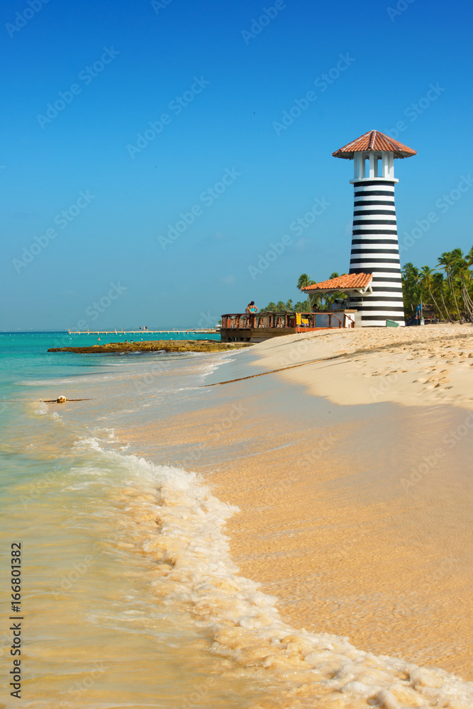 Fototapeta premium Striped red white lighthouse on the coast of the Caribbean Sea. Dominican Republic.