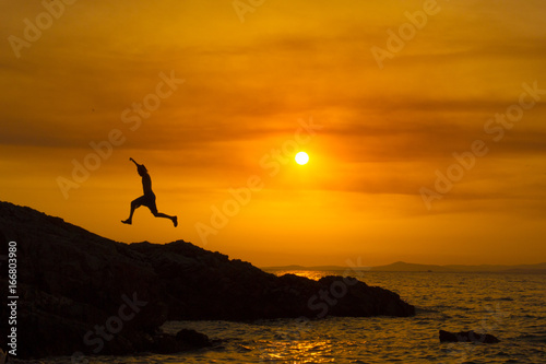 Man jumping rocks at sunset