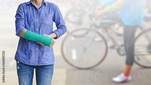 Female patient wearing blue shirt with green cast on arm isolated on blurred background woman riding a bicycle, body injury concept