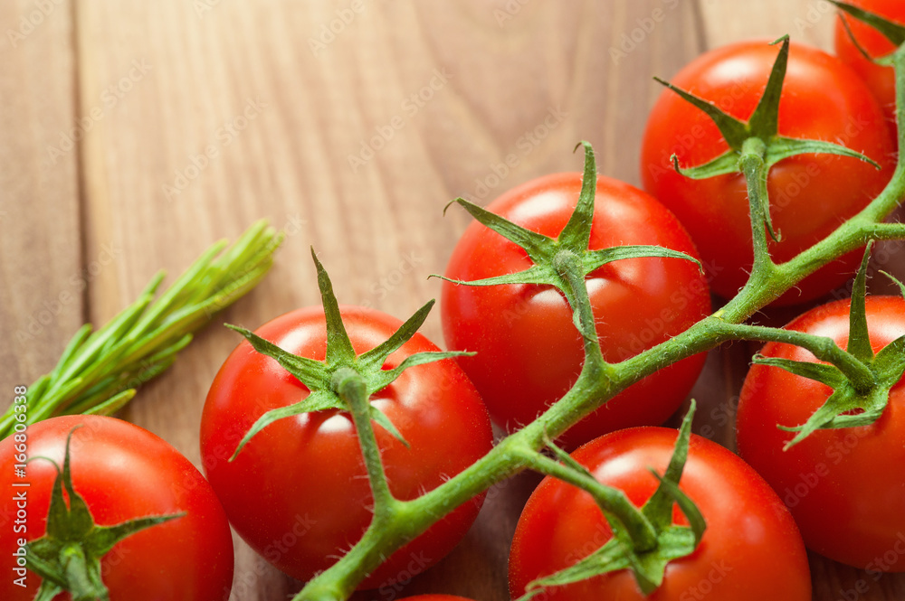 Branch of ripe cherry tomatoes over the wooden background