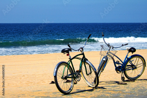 Two Bicycles, parked on a beach near the ocean