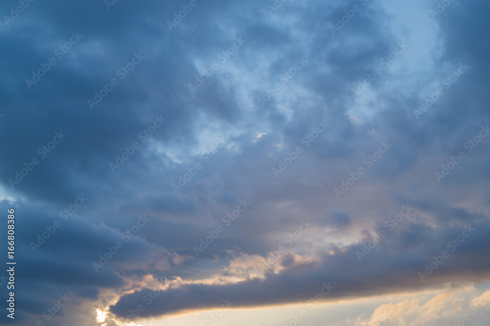 Fototapeta premium Grey and blue fkuffy clouds on the light-blue sky at sunset or sunrise