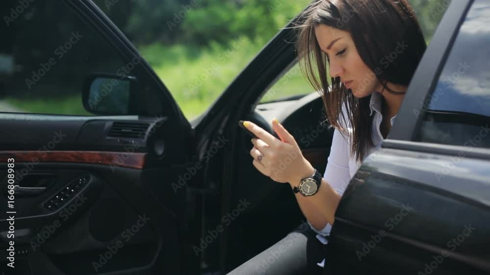 woman using holding looking smart phone sitting car open opened door moving camera closeup portrait trip gps searching internet pretty girl slowmotion serious calm tapping touching screen side view woman using holding looking smart phone sitting car open opened door moving camera closeup portrait trip gps searching internet pretty girl slowmotion serious calm tapping touching screen side view