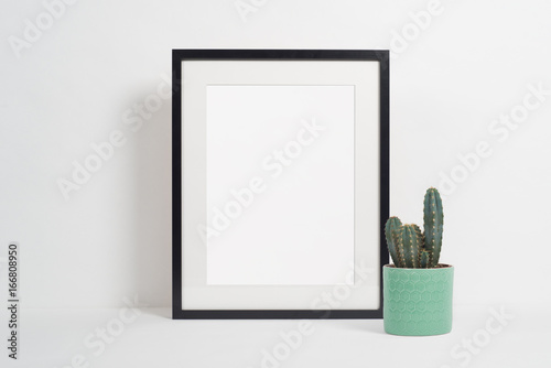 Black picture frame on white background with cactus