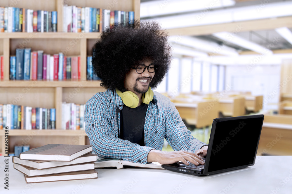 Afro student with a laptop and books