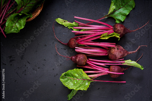 Young beetroot with a tops on a dark background. Flat lay. Top view.