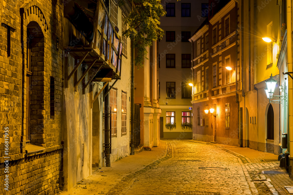 Night street in old Riga city, Latvia. Walking through medieval streets of old Riga tourists can feel unforgettable atmosphere of the Middle Ages and unique Gothic architecture