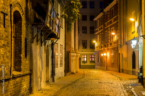 Night street in old Riga city, Latvia. Walking through medieval streets of old Riga tourists can feel unforgettable atmosphere of the Middle Ages and unique Gothic architecture