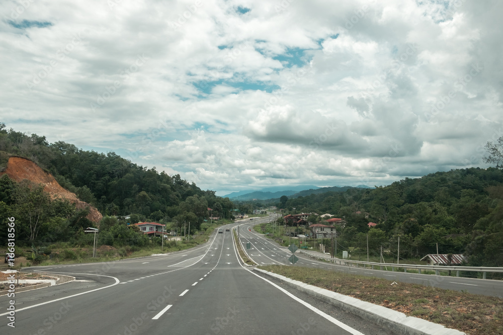 Dramatic scenic top view on curved asphalt road going to the mountains and sky. Target concept. Empty highway on Borneo island, Sabah, Malaysia