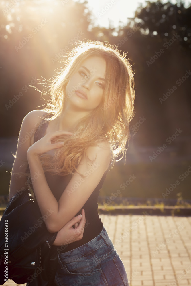 Beautiful young model with lush wave hair posing in rays of sun