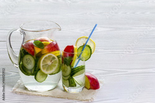 Detox water with cucumber and lemon with Apple in itcher and glass photo