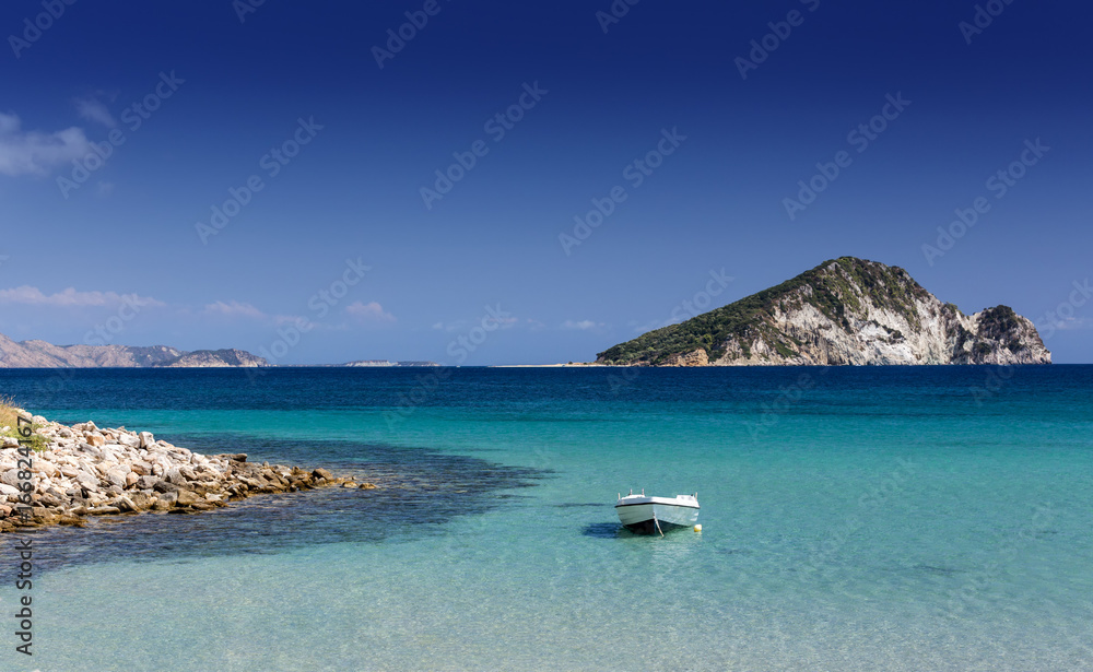 Beautiful scenery with the Ionian Sea. In the sea a white boat and on the horizon an island in the form of a turtle. Greece, Zakynthos.