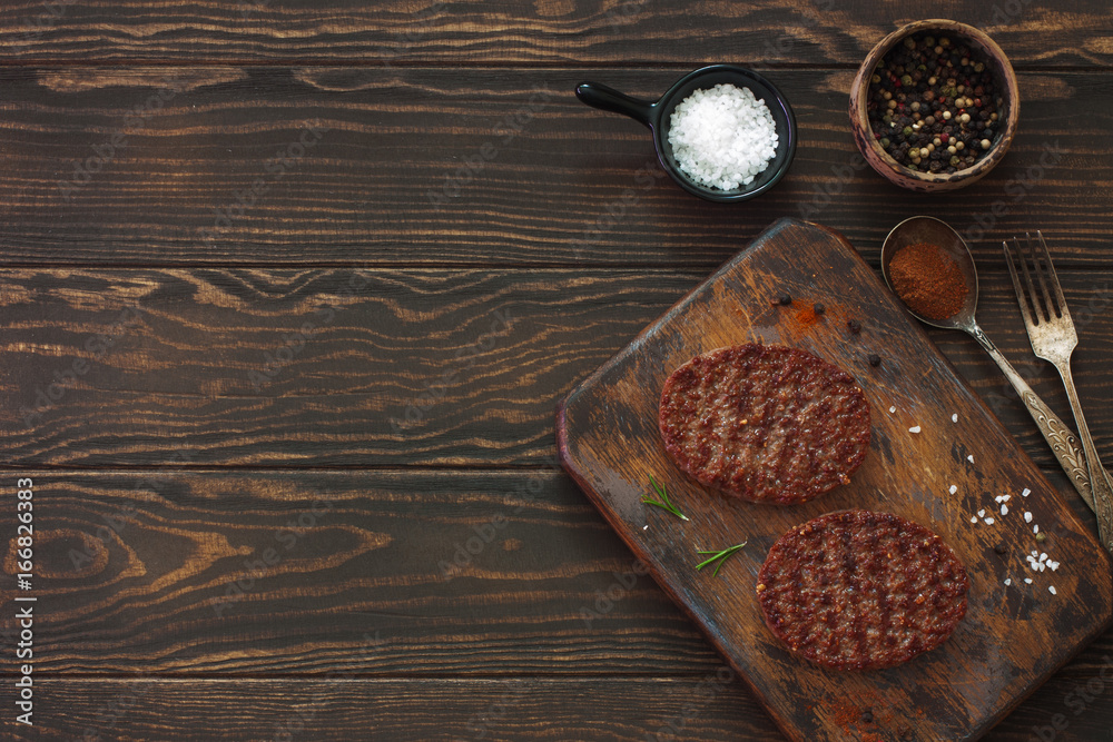 Two beefsteaks , peppers and old spoon, fork and cutting board over natural wood background