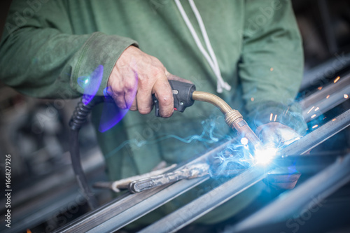 Industrial worker welding the steel structure in the workshop