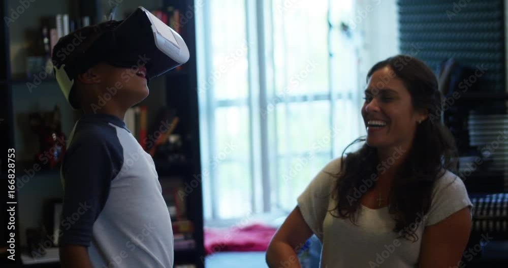 Slow Motion of boy playing with Virtual Reality headset as his mom watches and smiles Slow Motion of boy playing with Virtual Reality headset as his mom watches and smiles