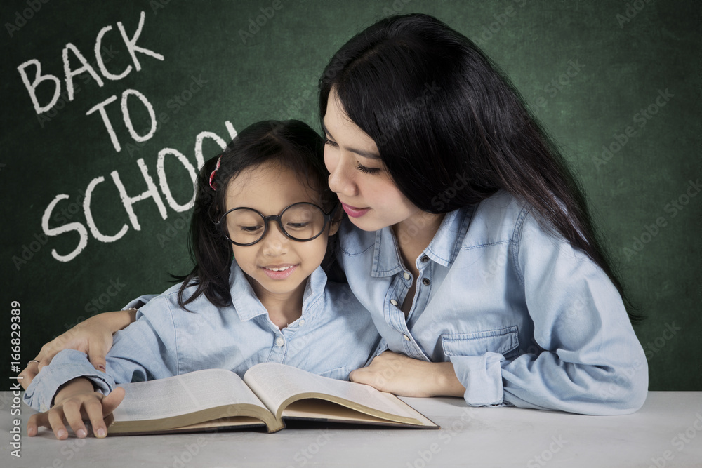 Teacher helps her student in the classroom Teacher helps her student in the classroom