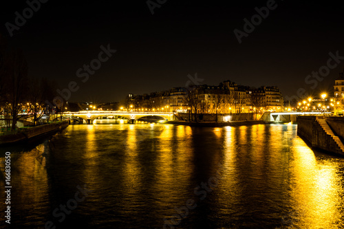 Night urban scene of a calm river crossing a big city © nadrilsan