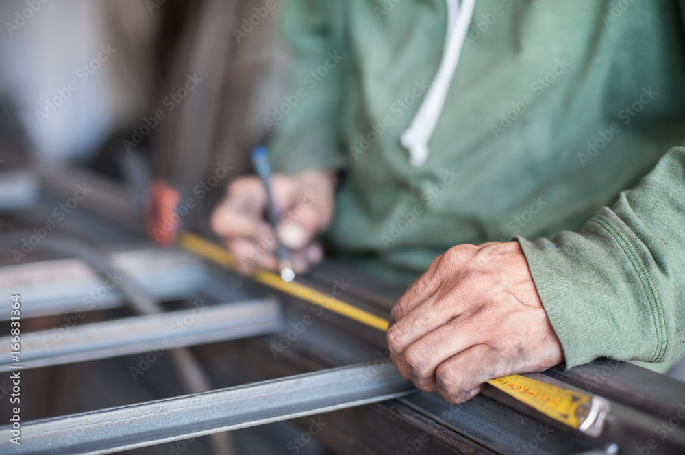 Worker measuring steel with measuring tape