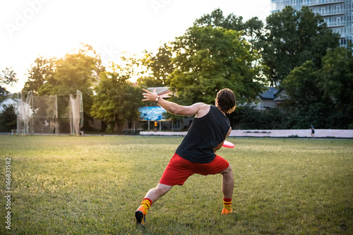 Young and athletic man playing frisbee in the park