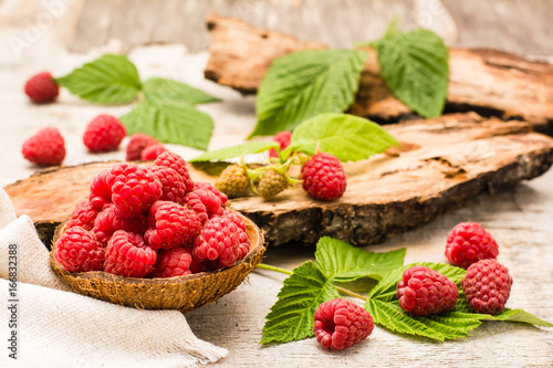 Raspberry in a bowl, berries and leaves on a shabby wood