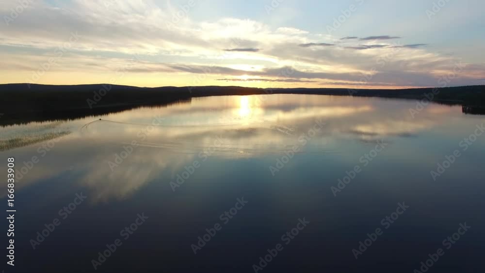 Flying up over lake in forest at sunest. Aerial shot of calm lake at dusk Flying up over lake in forest at sunest. Aerial shot of calm lake at dusk