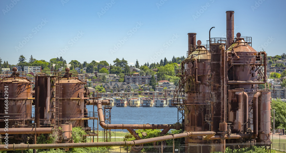 Abandoned machines and storage units in a gas industry at gas works park Seattle with homes behind