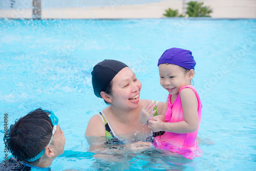 Asian mother and her children happy in swimming pool together