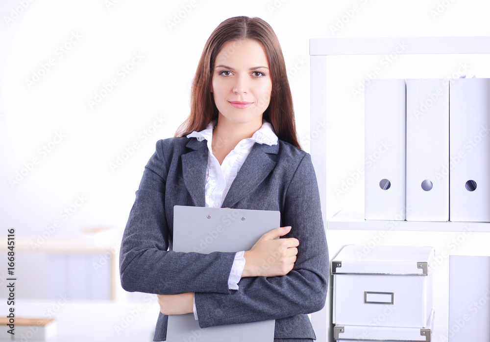 Attractive young businesswoman standing near desk in the office Attractive young businesswoman standing near desk in the office