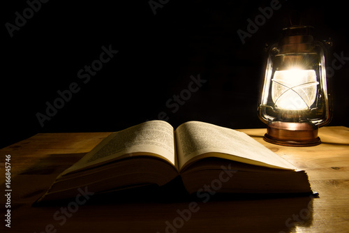 Open book illuminated by a storm lantern