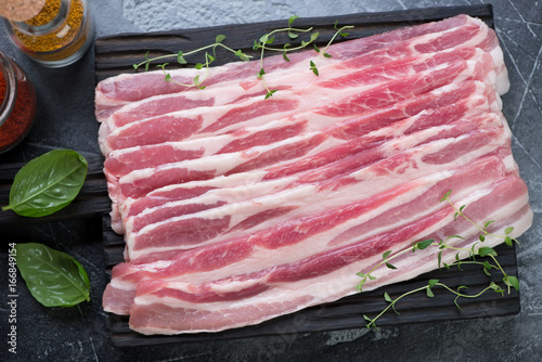 Close-up of fresh uncooked bacon with fresh thyme and basil, view from above