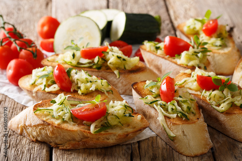 Bruschetta with grated zucchini and tomatoes close-up and ingredients. horizontal