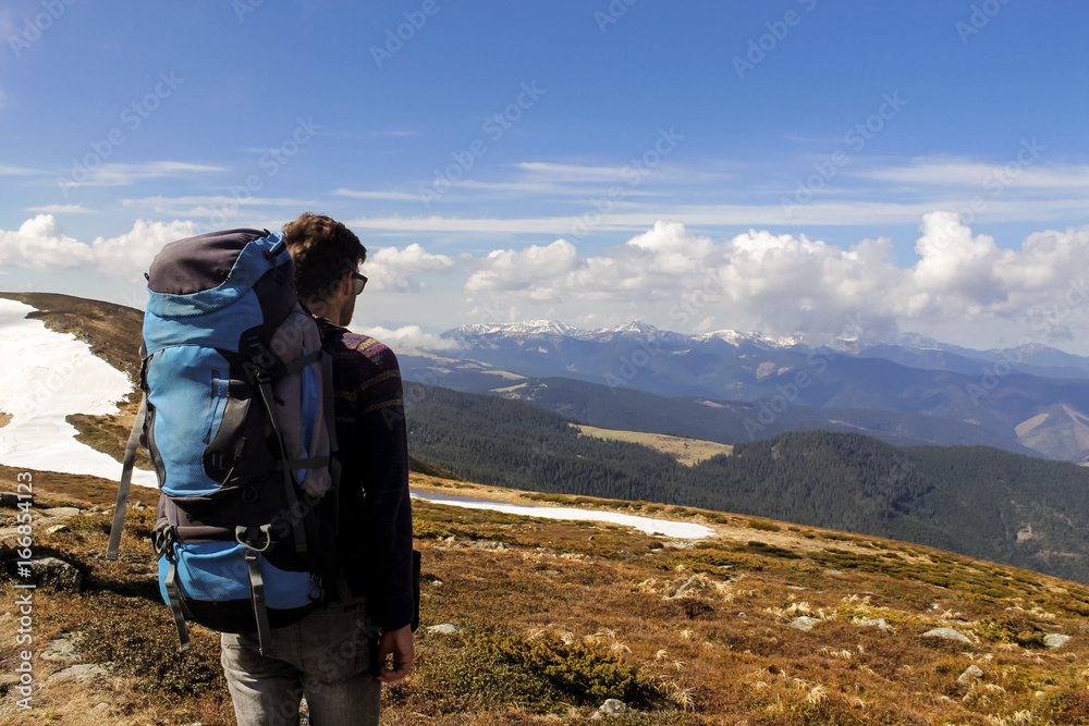 men hiker admiring looking into mountain valley during spring. snow covering the hills. nature landscape adventure 