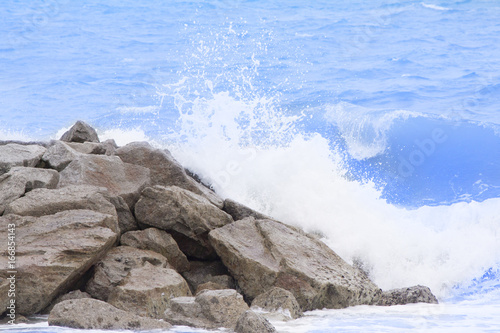 Sea wave to the beach with stone wall.
