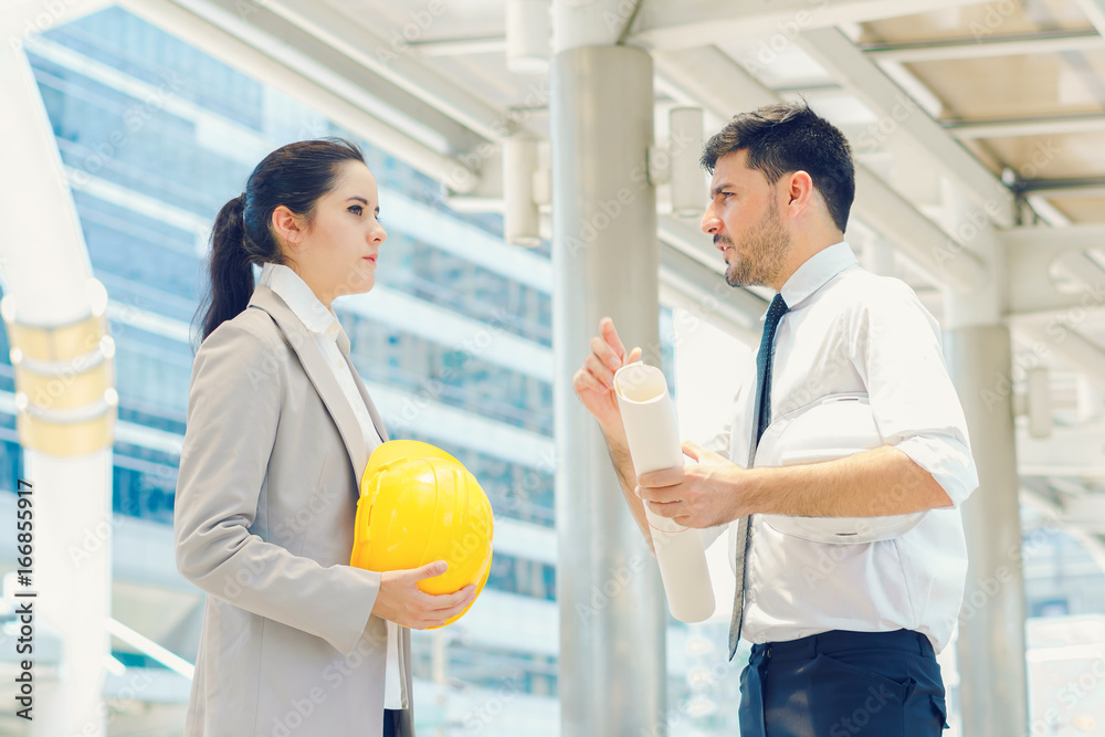 Obraz premium Engineer holding safety helmet and holding drawing discuss in building project planning, working together, concept of business negotiation and deal benefit.