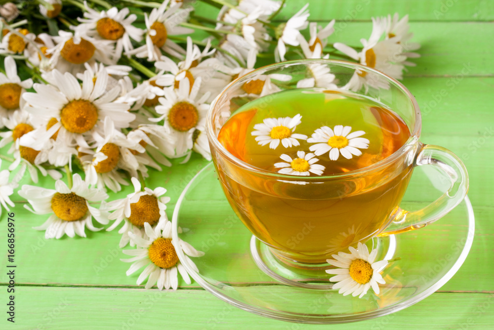 Herbal tea with fresh chamomile flowers on green wooden background Herbal tea with fresh chamomile flowers on green wooden background