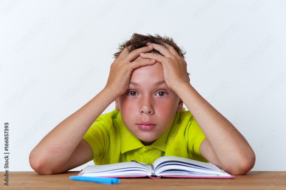 Tween boy sitting at the table with exercise book Tween boy sitting at the table with exercise book
