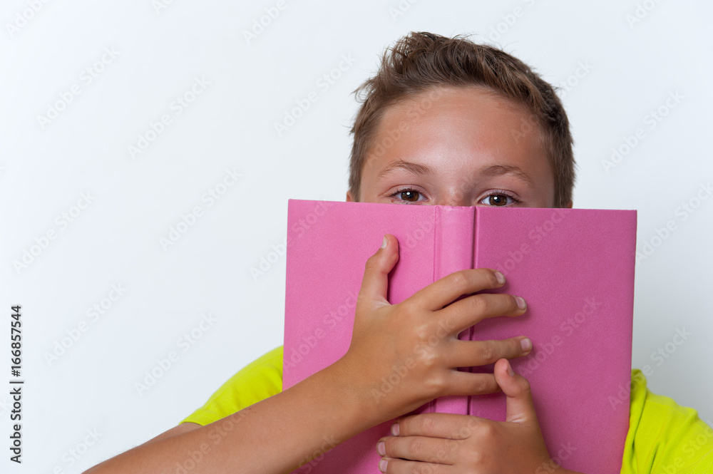 Tween boy covering his face with the book. Tween boy covering his face with the book.