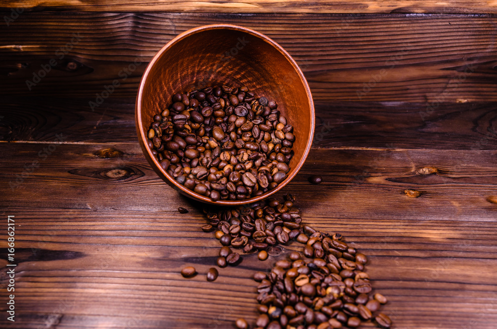 Roasted coffee beans in bowl on wooden table Roasted coffee beans in bowl on wooden table
