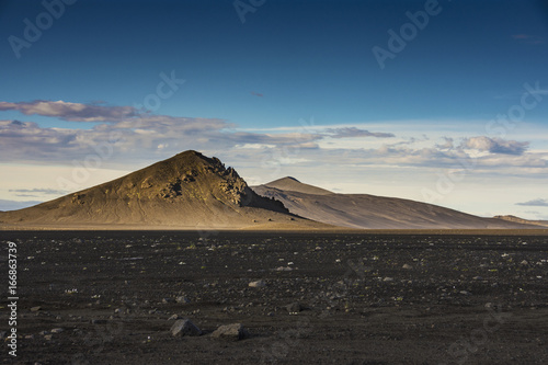 фотографія Brown isolated mountain with black volcanic ashes field and blue sky in summer,