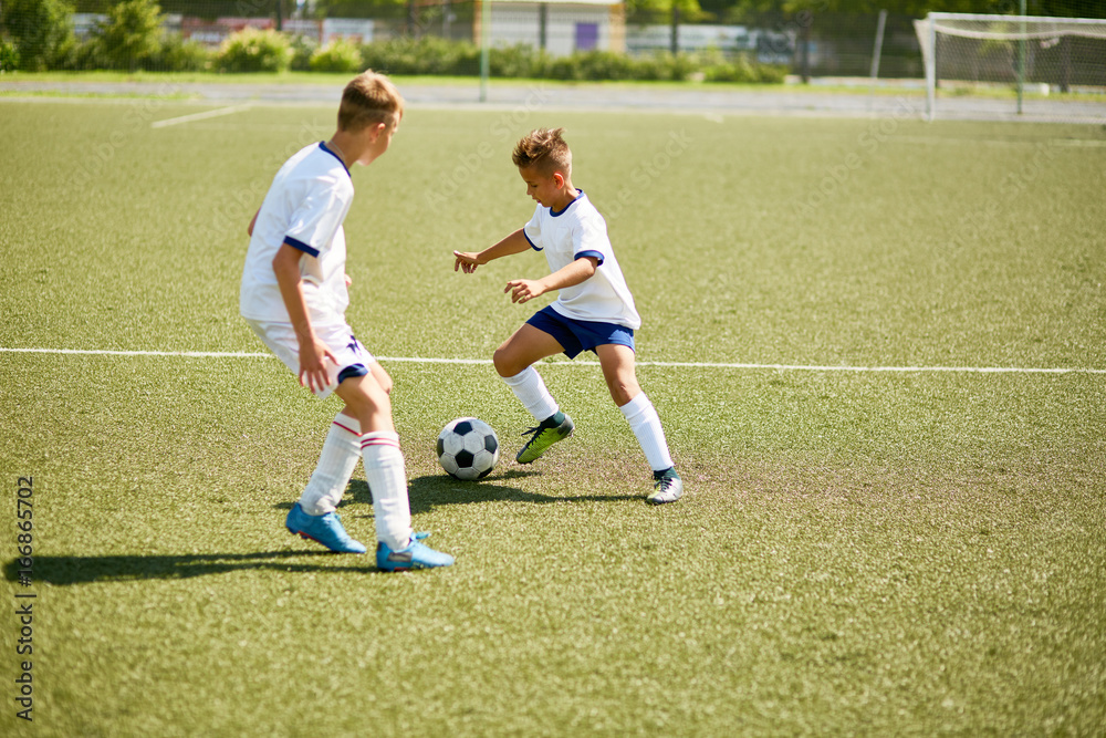 Obraz premium Boys Playing Football on Field