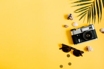 Flat lay traveler accessories on yellow background with palm leaf, camera and sunglasses. Top view travel or vacation concept. Summer background.