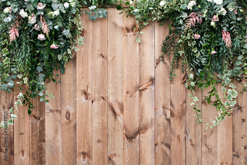 Fresh spring greens with white flower and leaf plant over wood fence background