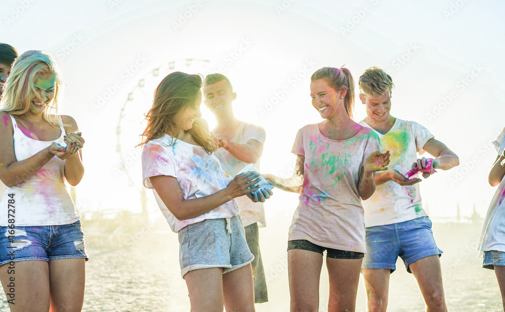 Happy friends making party at holi colors festival in summer time - Young people having fun on the beach event at sunset - Youth,positive mood and friendship concept - Focus on right girl face