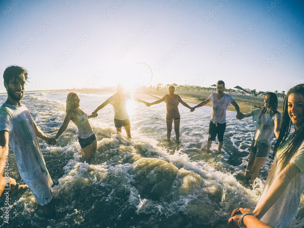 Pov view of happy friends having fun on the beach at sunset - Young people  playing inside
