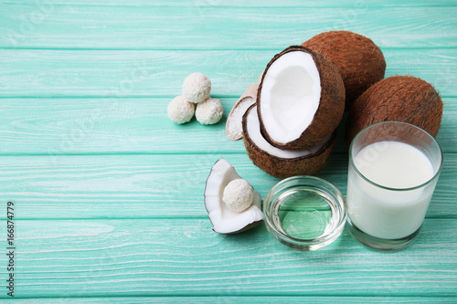 Coconuts with candies and bottle of milk on mint wooden table