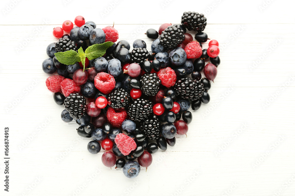 Berries in heart shape on white wooden table
