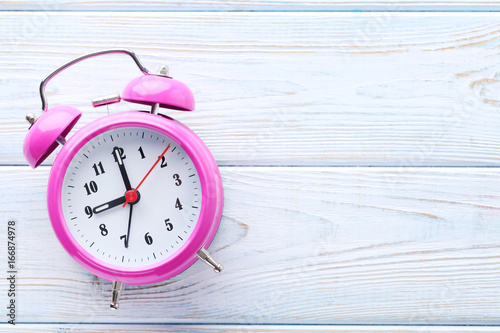 Pink alarm clock on white wooden table