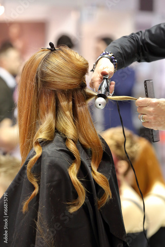 Hairdresser arranging hairdo by straightener